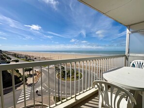 A balcony with a view of a beach and road.