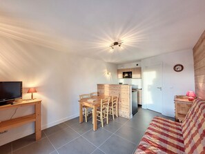 A compact living space with a dining area, kitchenette, and a television on a wooden stand. - Renovated studio, ski-in, south terrace (Montvalezan-La Rosière)