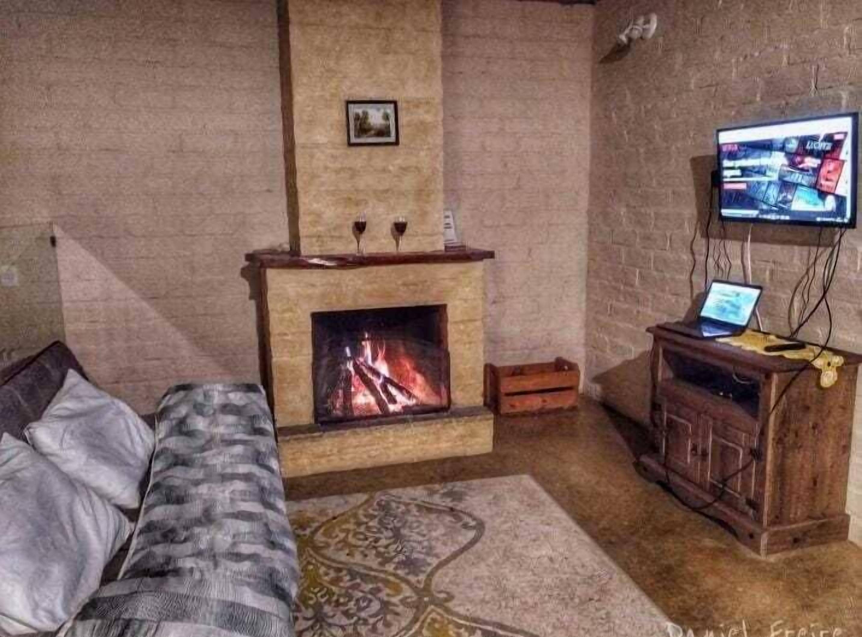 A cozy room with a fireplace, a sofa, a TV, and a wooden cabinet.
