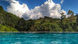A coastal landscape with clear blue waters, green hills, and a forested area. - MD LUAR DA MONTANHA (Camanducaia)
