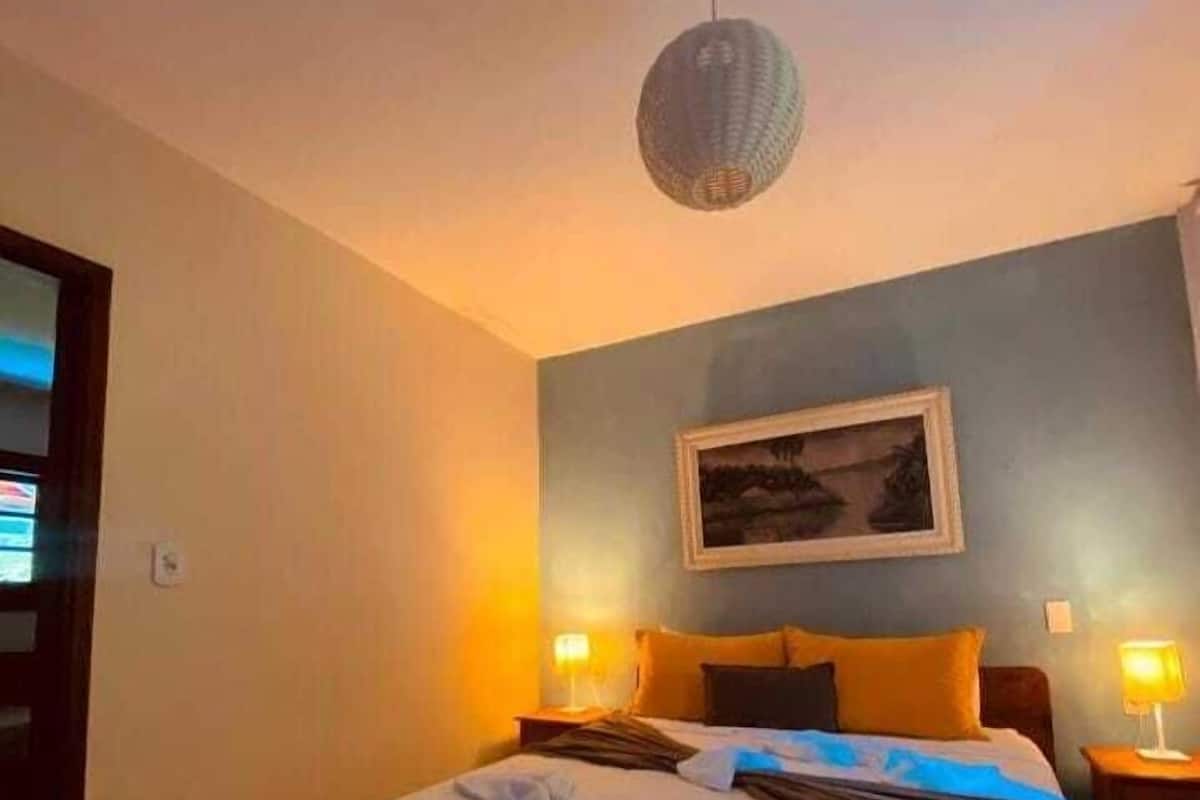 A hotel room with a large bed, two bedside lamps, a framed picture on the wall, and a ceiling light fixture.