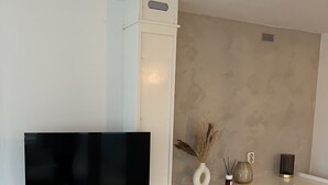 A modern living room with a flat-screen TV, a fireplace, and a white cabinet with drawers. - Chalet Quattro in Bosrijke Omgeving Anloo (Anloo)