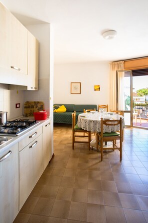 A compact kitchen with white cabinets, a stove, and a dining area with a table and chairs.