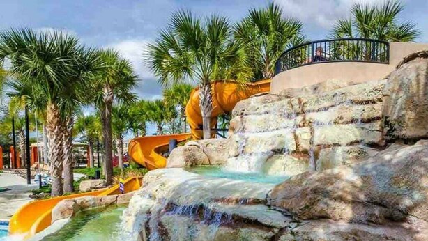 A water park with a waterfall, palm trees, and a slide. - 7495 OL - Solterra Resort (Davenport)
