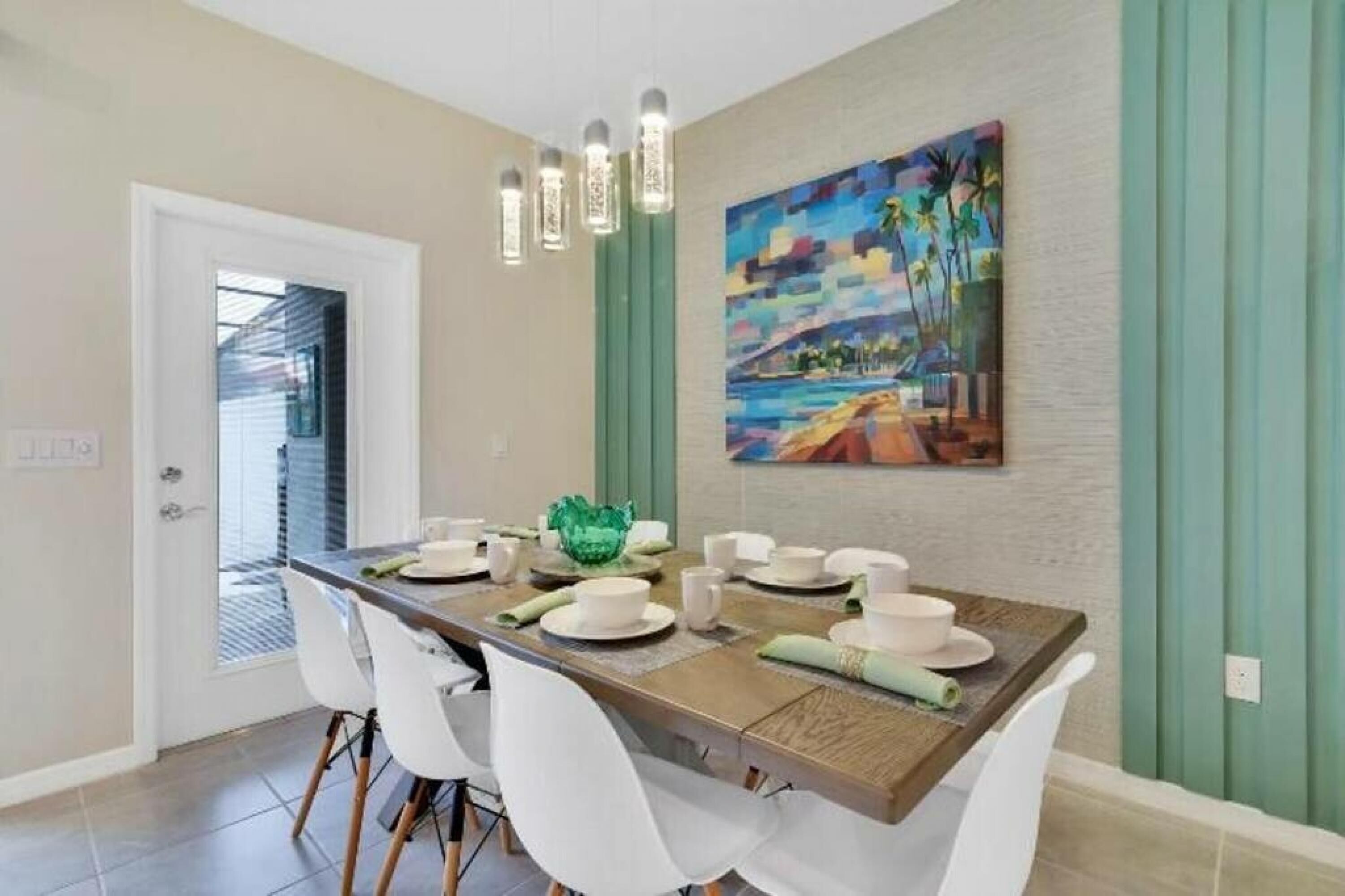 A dining area with a wooden table set for four, white chairs, and a green decorative bowl.