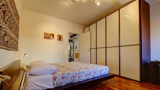 A modern bedroom with a bed, wooden flooring, a wardrobe, and a mirror. - LA CASETTA (Venezia)
