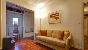 A living room with a beige sofa, a floor lamp, and a window. - LA CASETTA (Venezia)