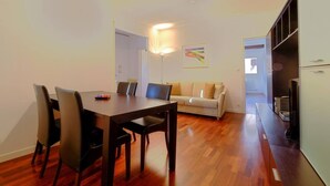 A modern living room with a wooden dining table, a beige sofa, and a flat-screen TV. - LA CASETTA (Venezia)