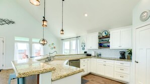 A spacious kitchen with white cabinets, granite countertops, and pendant lighting. - Saltwater Soul - Cool Unique Mid-Level Hangout Area! (Surfside Beach)