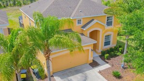 A two-story house with a garage, surrounded by palm trees and a well-maintained lawn. - 1078 OC - Watersong in Davenport (Davenport)