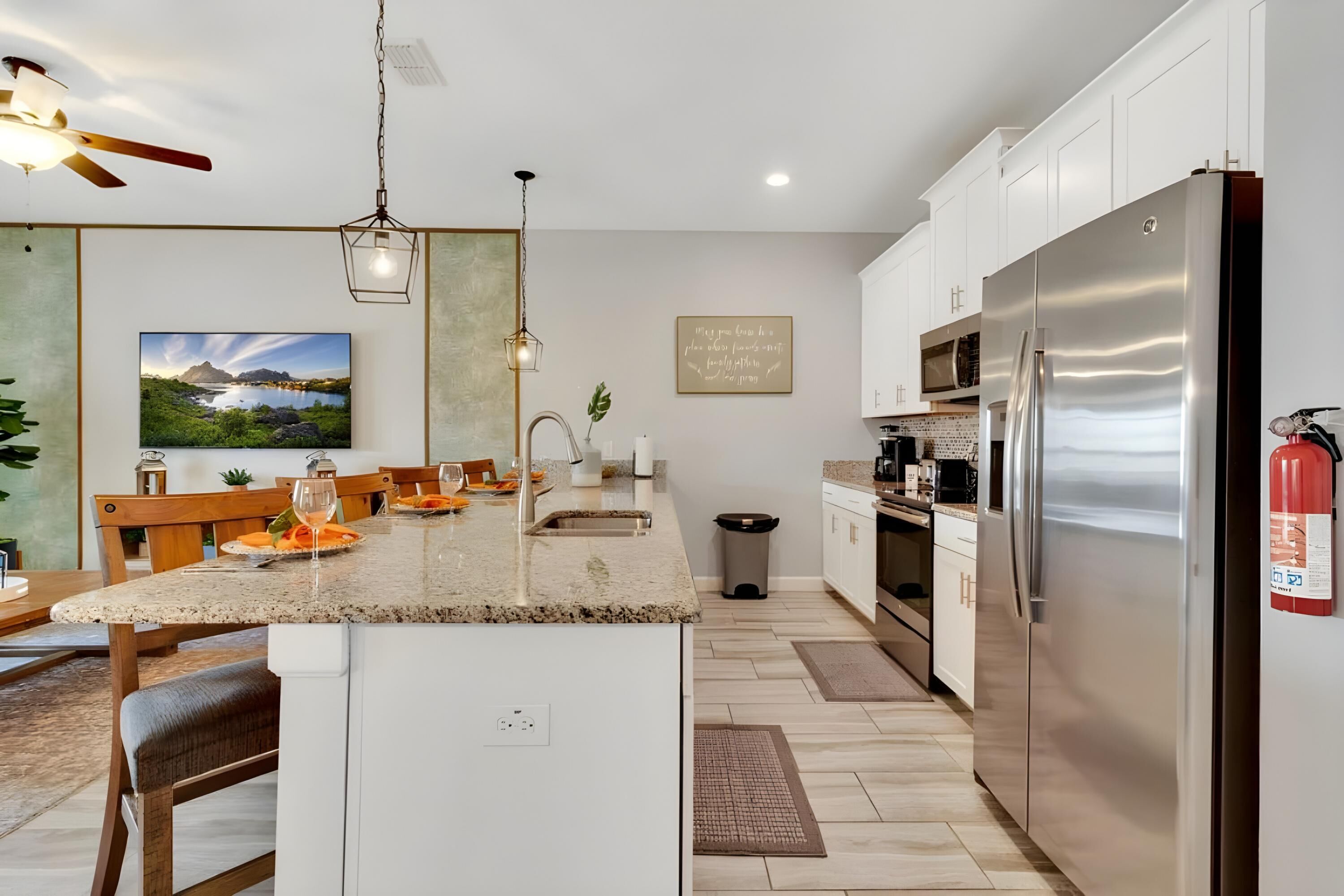 A modern kitchen with a central island, stainless steel appliances, and a dining area with a view of a scenic landscape.