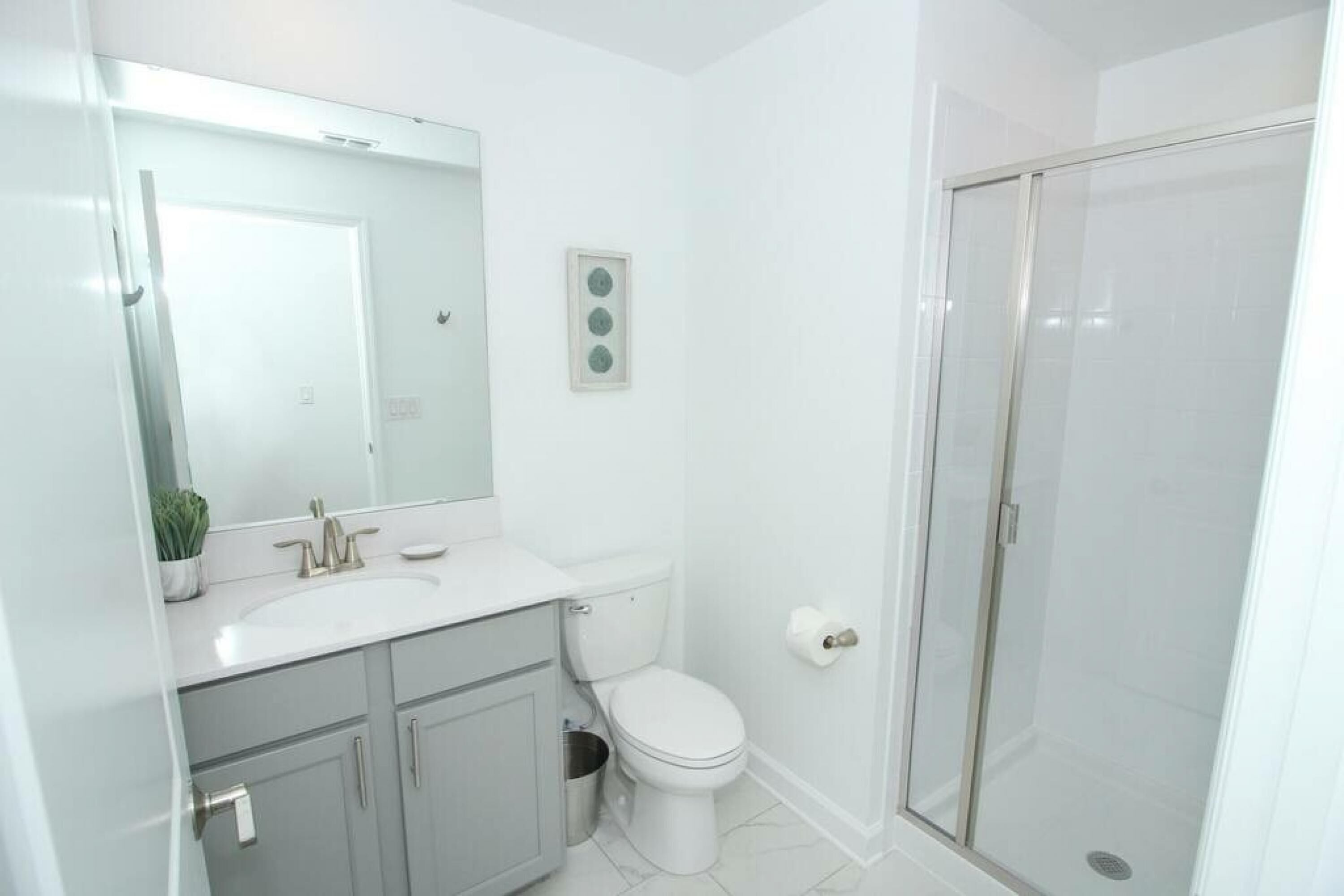 Une salle de bain moderne avec un lavabo, des toilettes et une douche, le tout de couleur blanche.