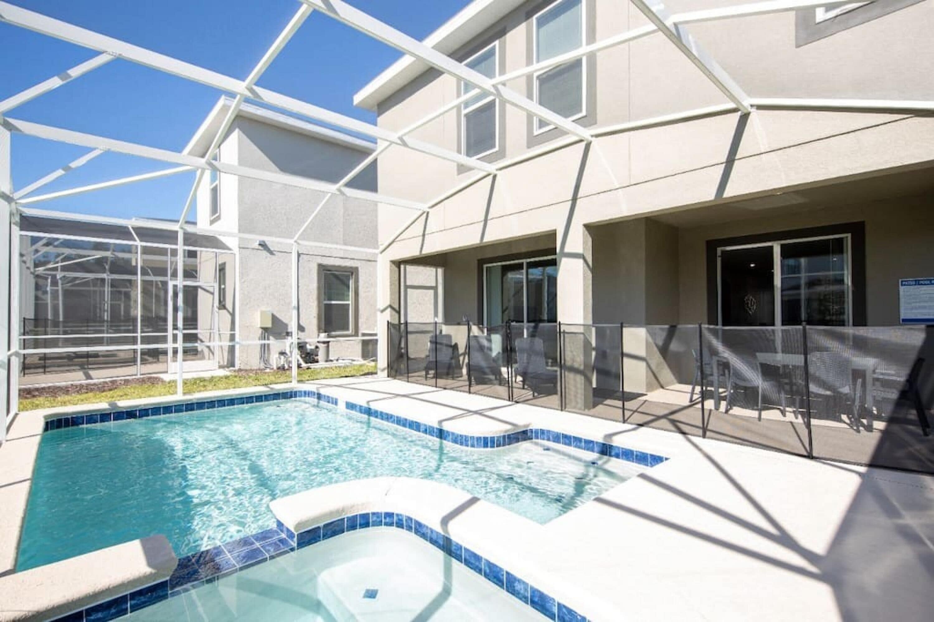 Ein Schwimmbad mit Whirlpool, umgeben von einer überdachten Terrasse mit Stühlen und Tischen.