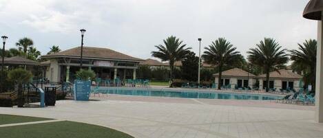 Zona de piscina con sillones de descanso y palmeras.