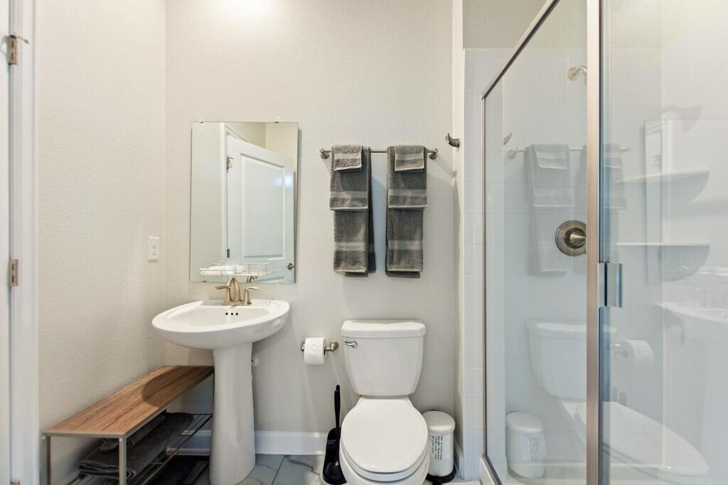 A modern bathroom with a white sink, toilet, and glass shower enclosure.