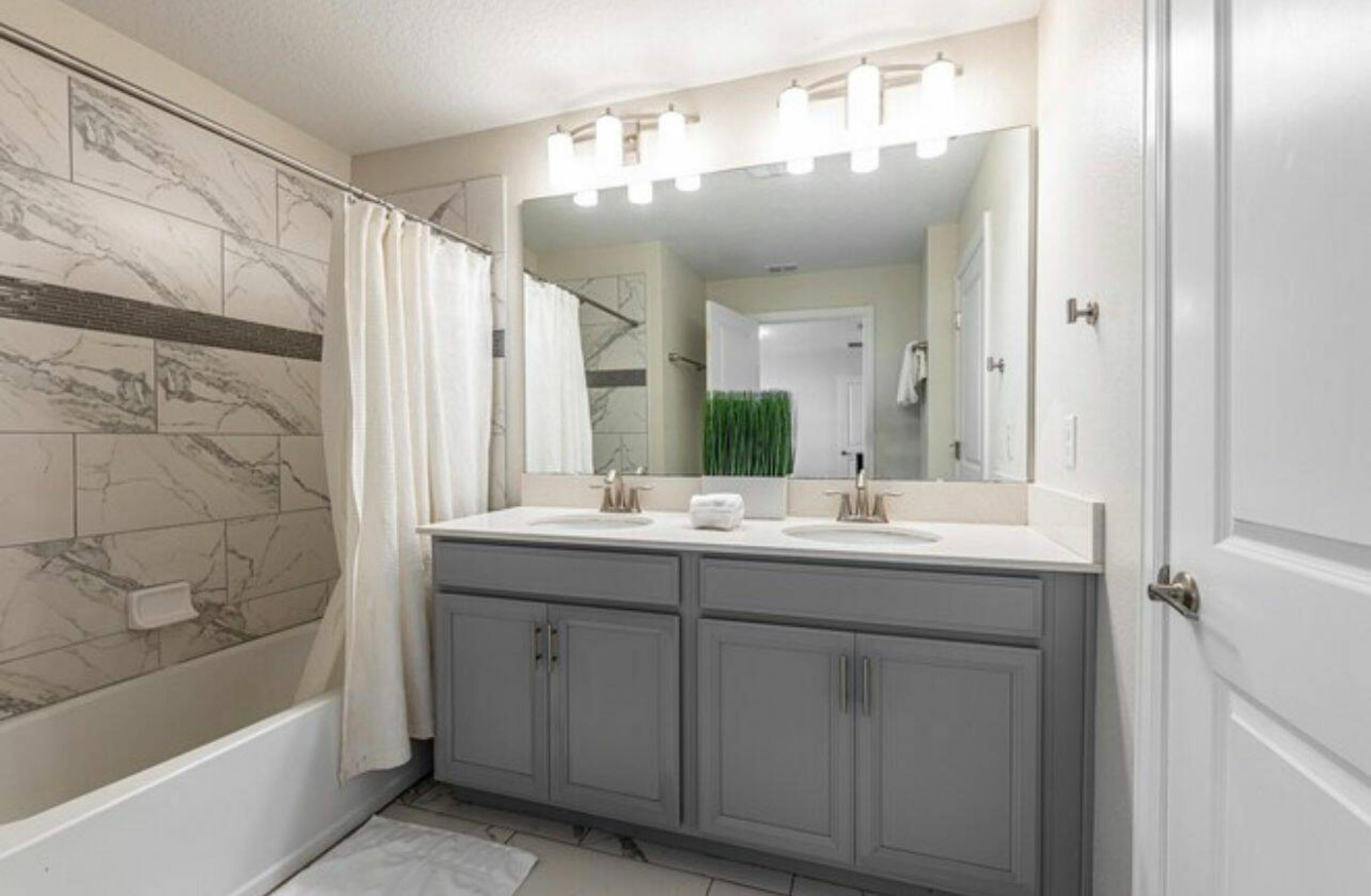 A bathroom with a double sink vanity, a large mirror, and a shower curtain.