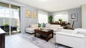 Ein großzügiges Wohnzimmer mit einer großen Couch, einem Couchtisch und einem Essbereich mit Tisch und Stühlen.