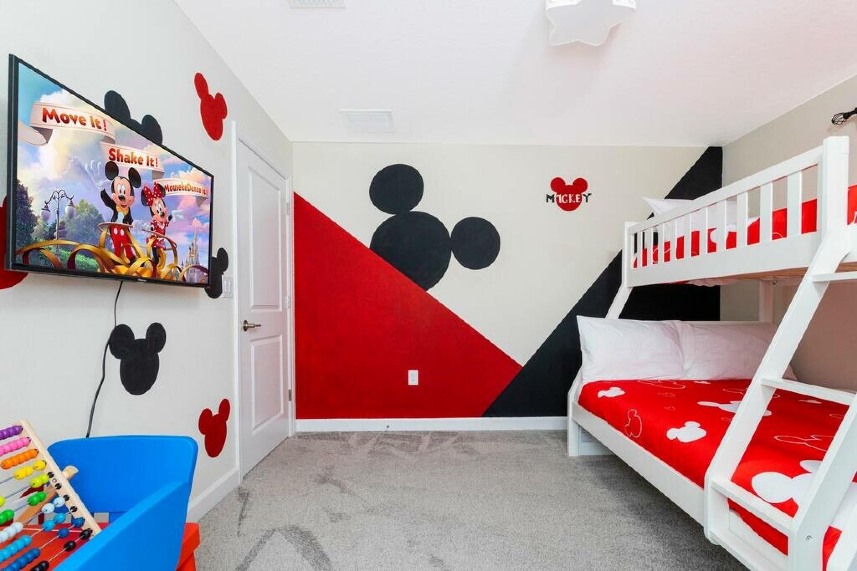 Ein Kinderzimmer mit Fernseher, Etagenbett und Mickey Mouse Dekoration.