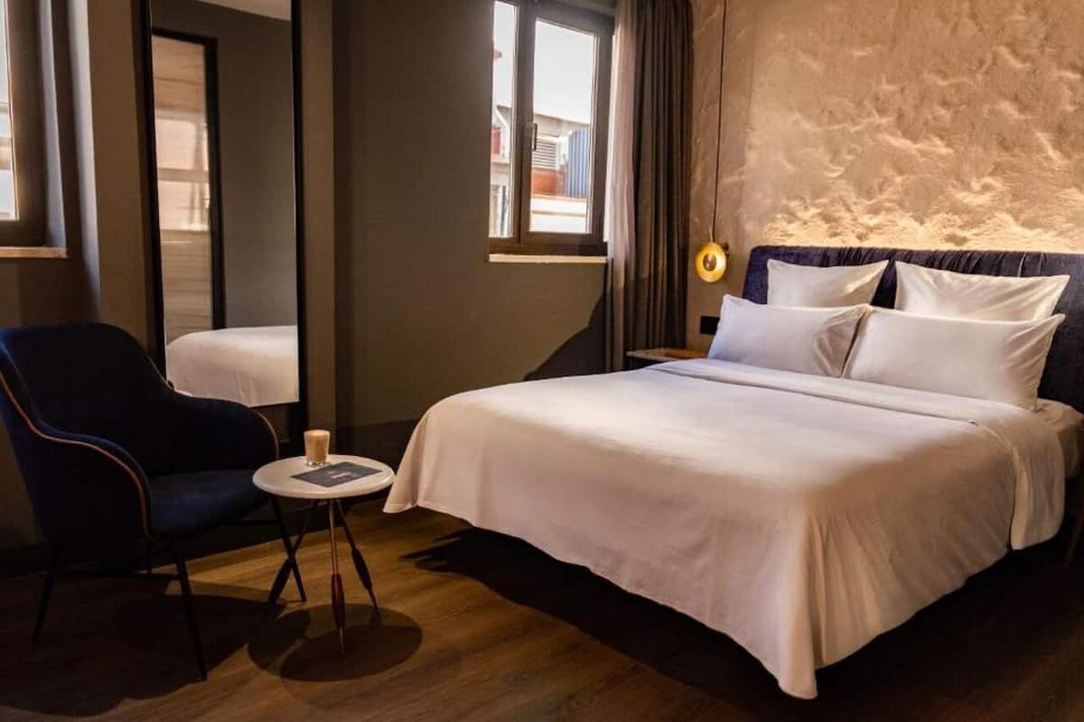 Une chambre d’hôtel avec un lit, une chaise, une petite table et une fenêtre.