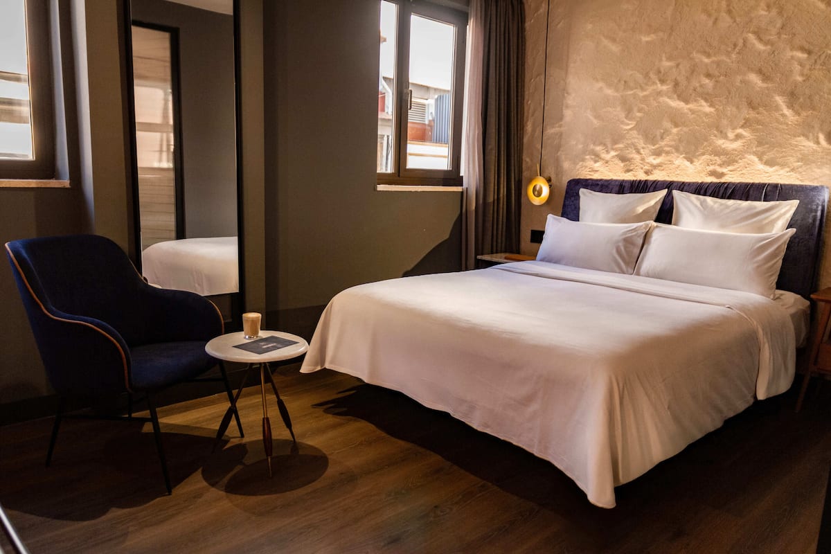 Une chambre d’hôtel avec un lit, une chaise, une petite table et une fenêtre.