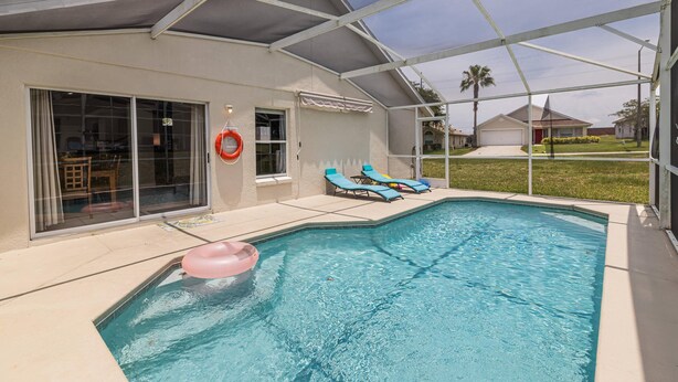 A swimming pool with a covered patio area, lounge chairs, and a glass door leading to an interior space. - 173 Hillside Dr in Davenport (Davenport)