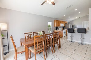 A modern kitchen with wooden cabinets, a central island, and a dining area with a wooden table and chairs.