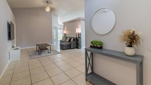 A spacious living room with a grey sofa, a coffee table, and a console table with a mirror and plants. - 173 Hillside Dr in Davenport (Davenport)