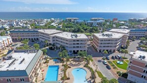 Un hotel con varias construcciones, una piscina central y vista al océano.