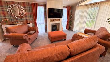 A living room with a fireplace, a television, and a plaid curtain.