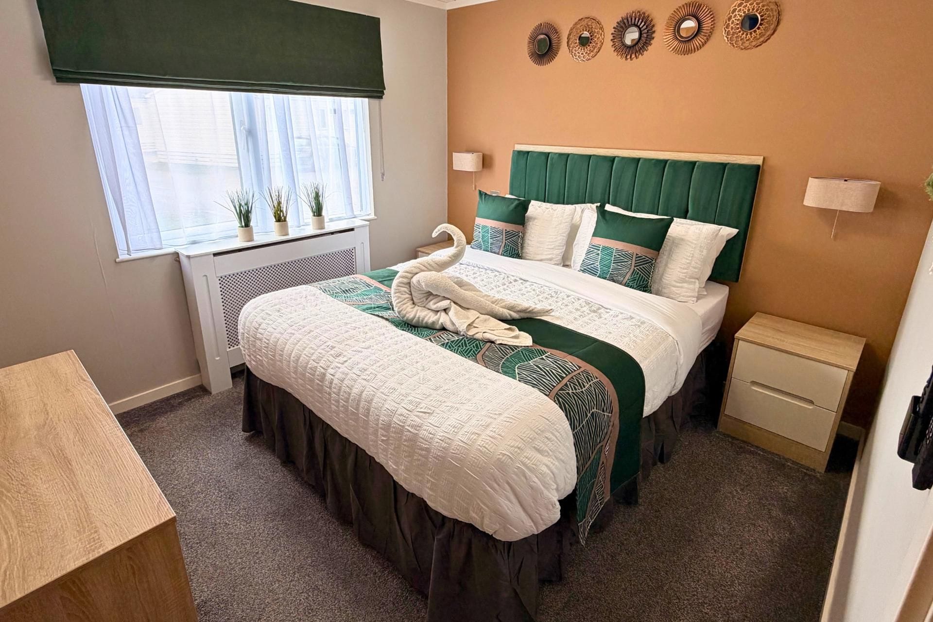 A bedroom with a bed, bedside tables, a window with blinds, and wall decor.