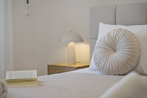A neatly made bed with a pillow, a bedside lamp, and a book on the nightstand.