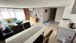 A modern living room with a sofa, dining table, and kitchen area.