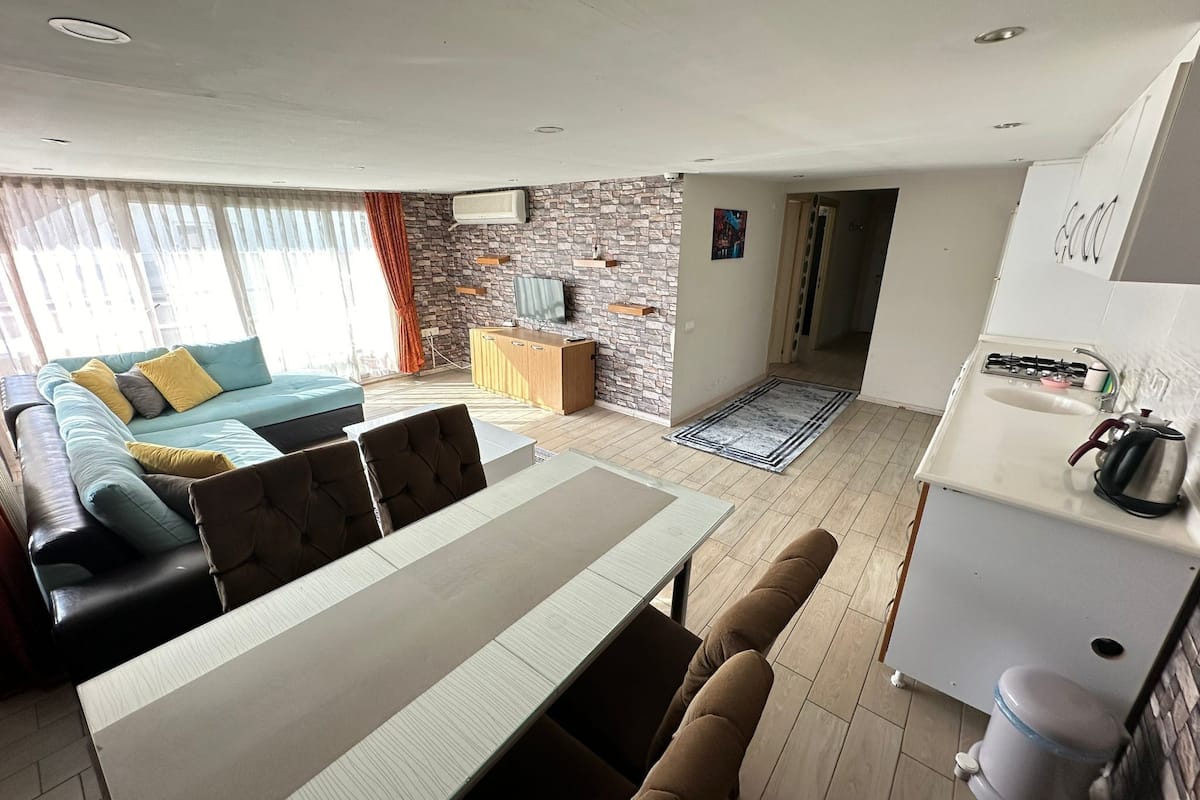 Een moderne woonkamer met een bank, eettafel en keukenhoek.