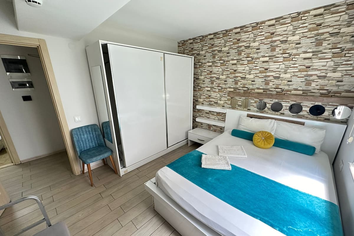 Een moderne slaapkamer met een groot bed, een kledingkast, een stoel en een wand met steenmotief.