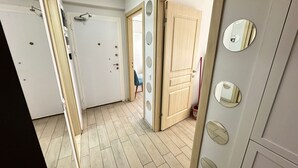 A hallway with wooden flooring, white walls, and a door with circular mirrors.