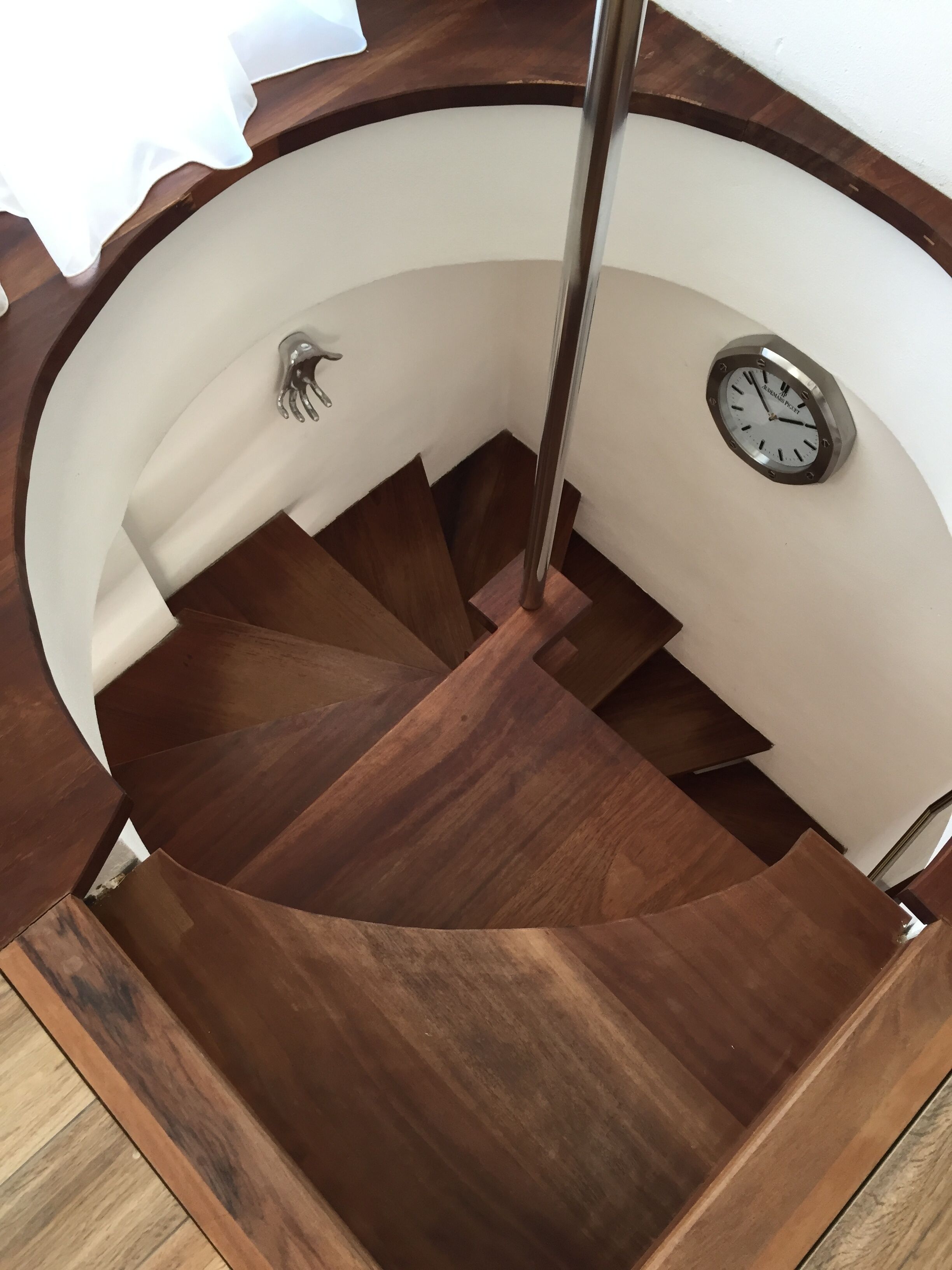 A spiral staircase with wooden steps and a clock on the wall.