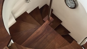 Una escalera de caracol con escalones de madera y un reloj en la pared.