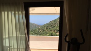 Una habitación con vista a una colina y un cuerpo de agua.