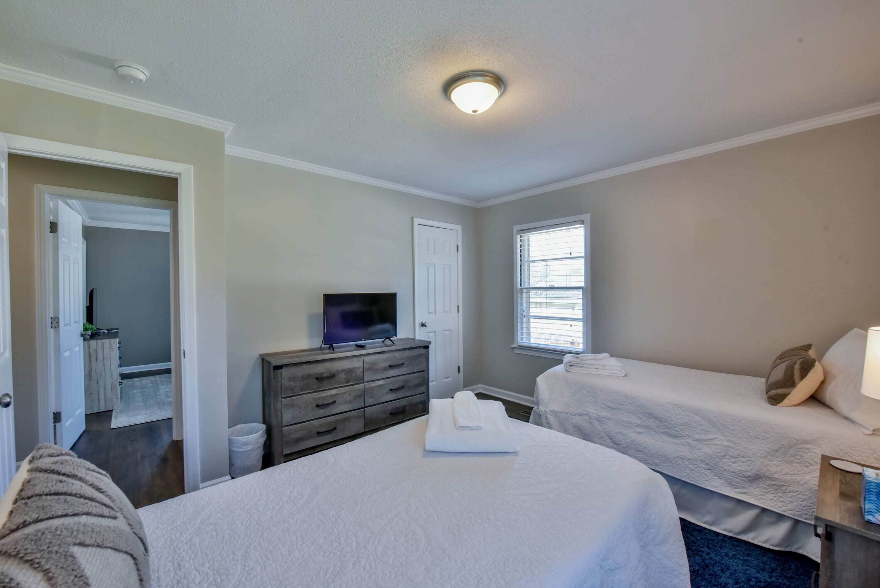 Een hotelkamer met twee bedden, een televisie, een dressoir en een raam.