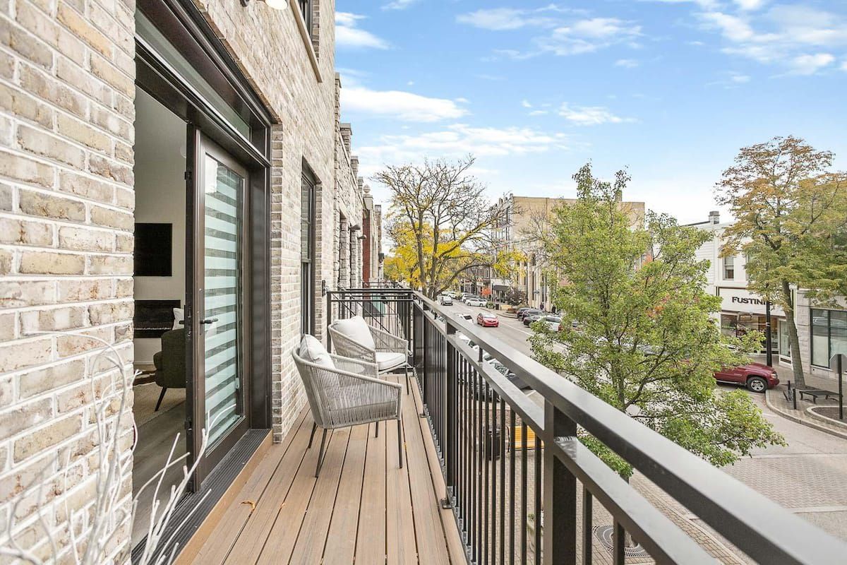 Ein Balkon mit Blick auf eine Straße, ein Backsteinhaus und ein Geschäft.