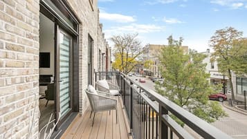 A balcony with a view of a street, a brick building, and a storefront.