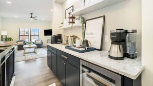 A modern kitchen with a marble countertop, a Keurig coffee maker, and a framed artwork on the wall.