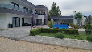 A modern multi-story building with a swimming pool, outdoor seating, and well-maintained landscaping.