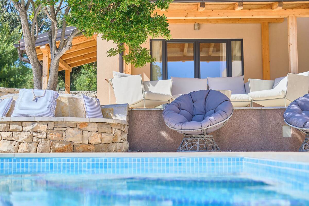 A pool area with lounge chairs and a stone wall.