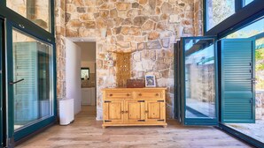 A stone wall, wooden cabinet, and glass doors in a room. - Resort Amalka Mare by Litto (Trogir)