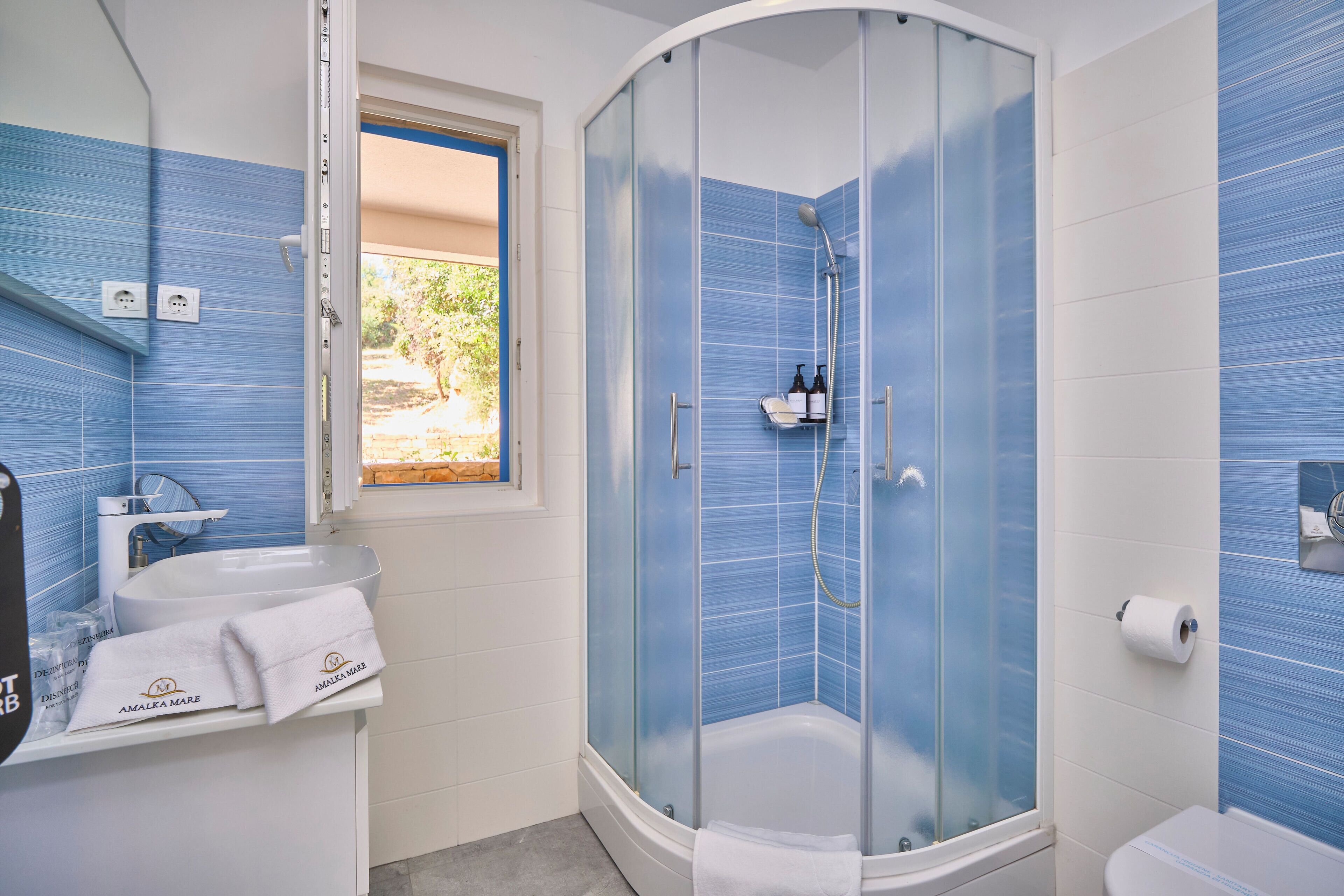 Ein Badezimmer mit einer Duschkabine, einem Waschbecken mit Handtuch und einer Toilette.