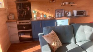 Zona d'estar acollidora amb un sofà, cuina amb fogó i microones.