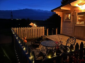 A wooden cabin with a deck, a table, and chairs. - Captivating 1-bed Lodge in Chesterfield (Chesterfield)