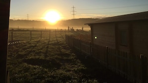 A rural landscape with a wooden building, a fence, and power lines in the background. - Cosy 1-bed Farm Stay Cabin (Chesterfield)