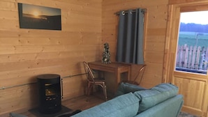 A cozy cabin interior with a sofa, a table, and a fireplace. - Cosy 1-bed Farm Stay Cabin (Chesterfield)